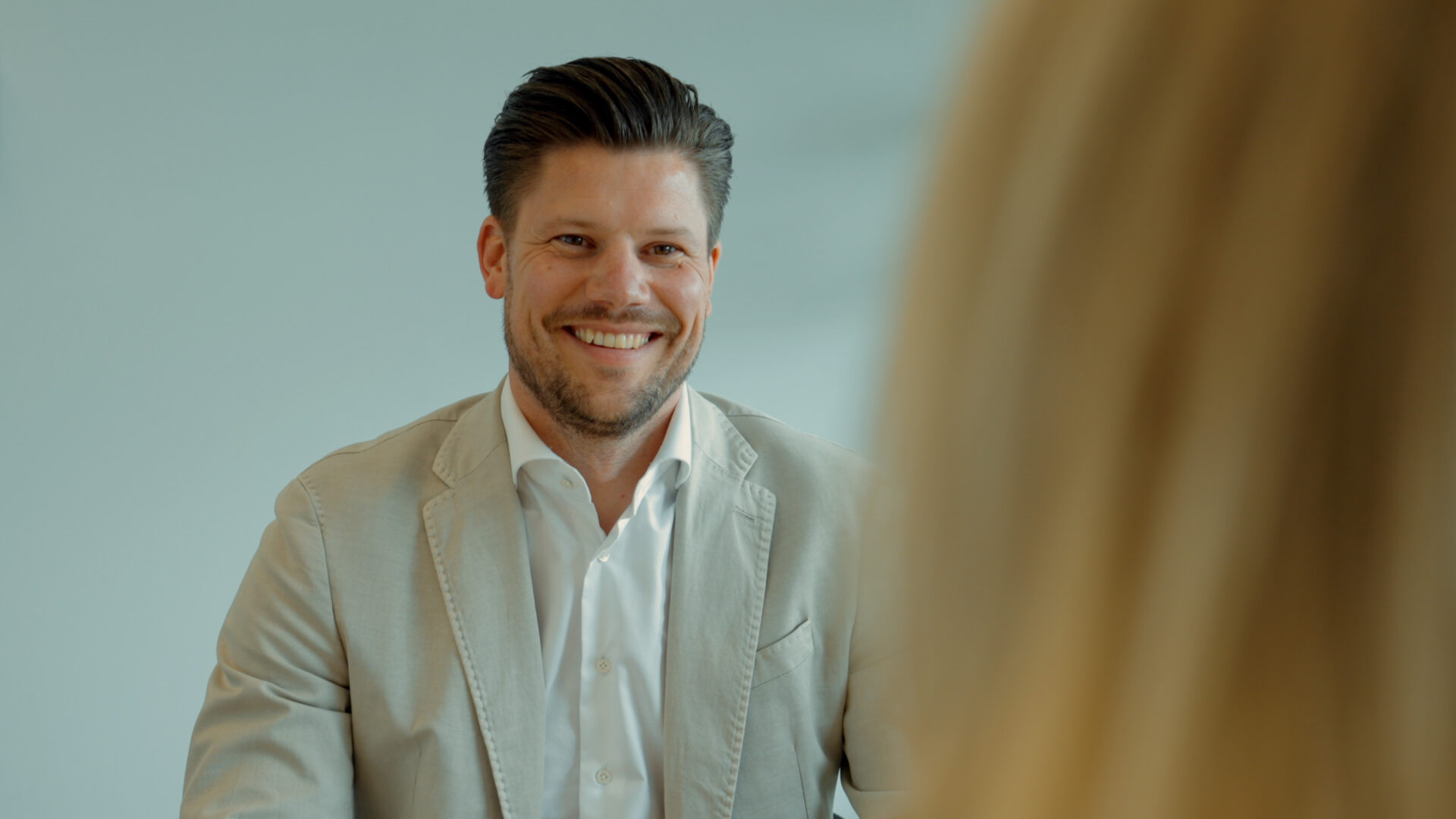 Een glimlachende medewerker van Vonders in een net colbert tijdens een overleg op kantoor over detachering in de infra.